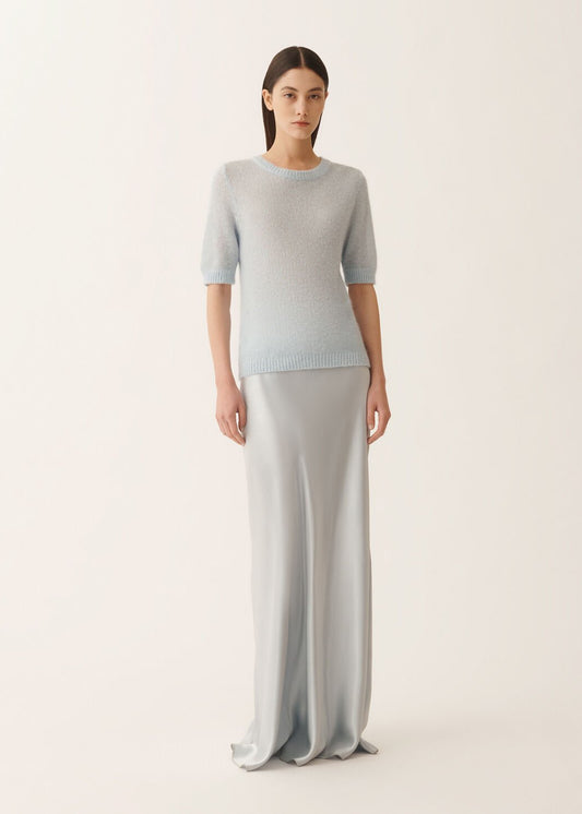 Woman wearing a light blue sweater and gray pants on a white background