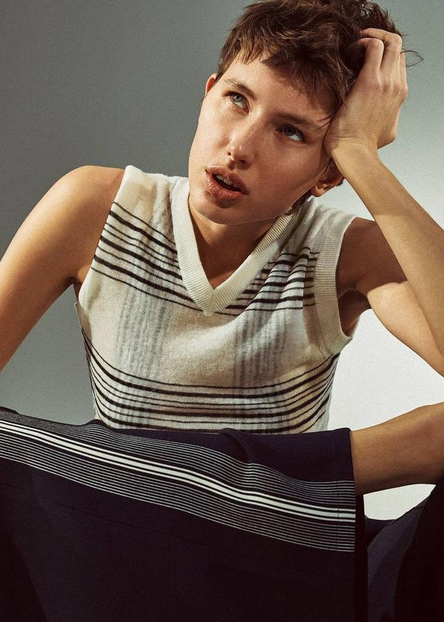 Person wearing a sleeveless striped top against a neutral background