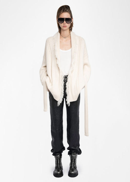 Person wearing a white cardigan, black pants, and black boots on a white background