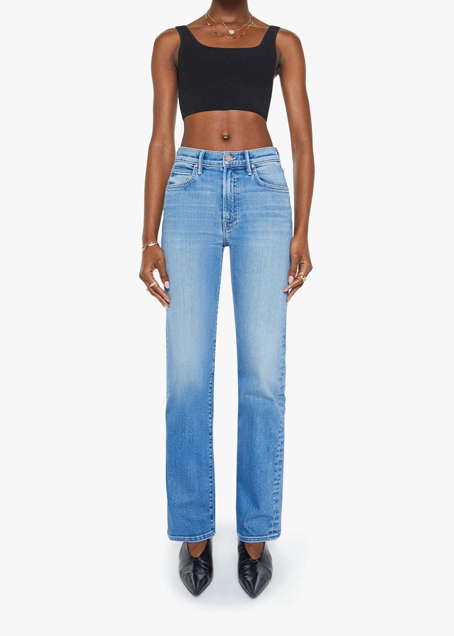 Person wearing blue jeans and a black top on a white background