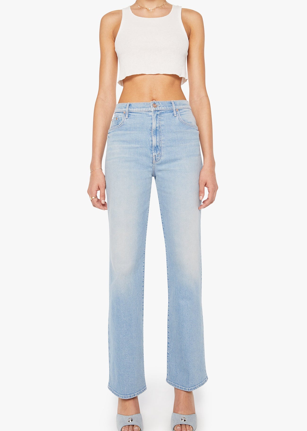 Person wearing light blue jeans and a white crop top on a white background