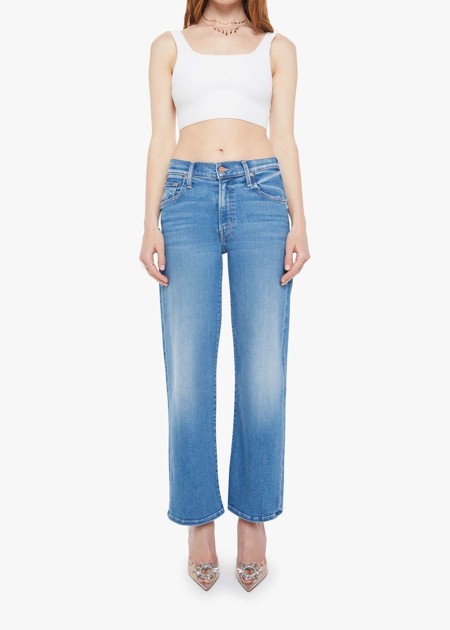 Woman wearing a white crop top and blue jeans on a white background