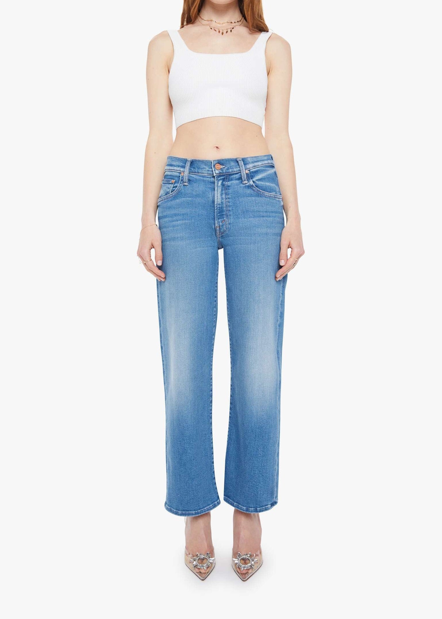 Woman wearing a white crop top and blue jeans on a white background