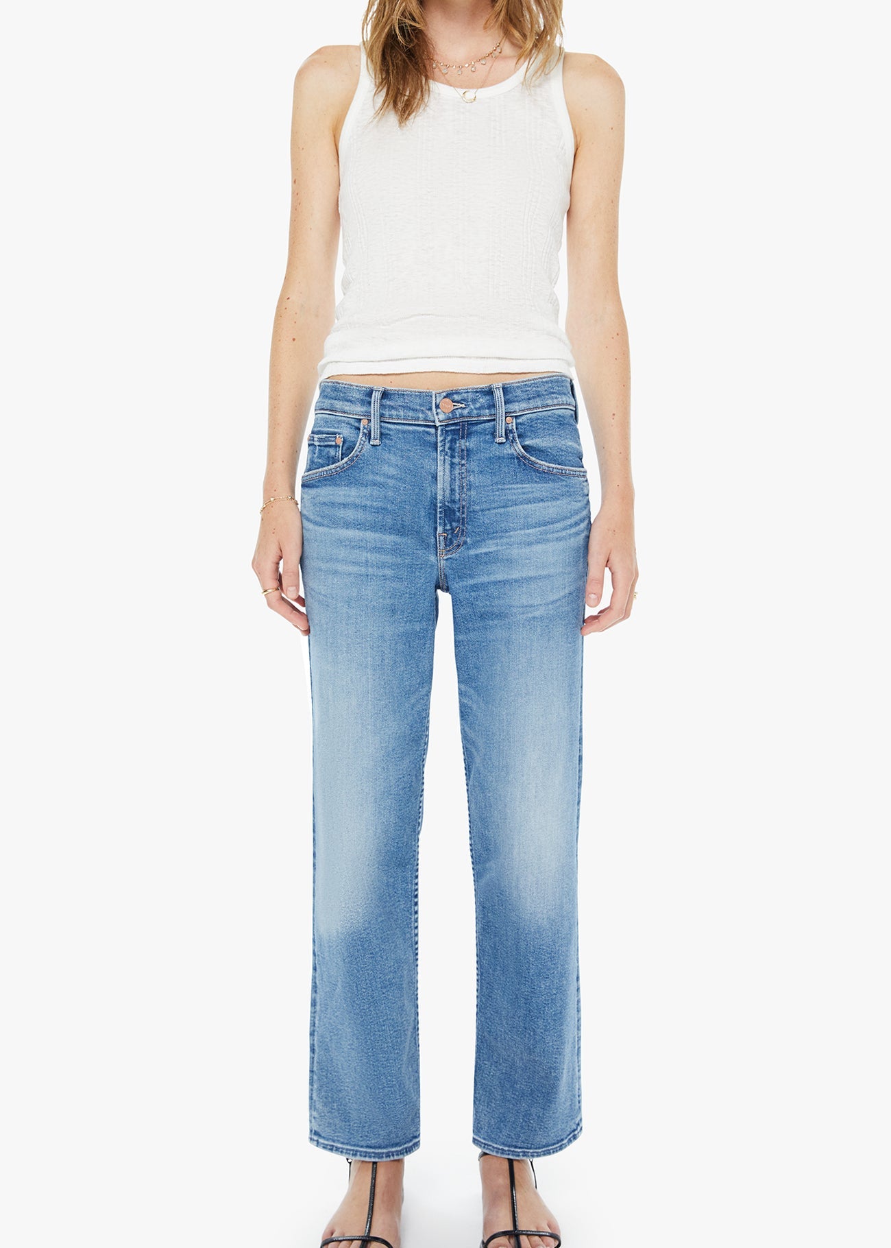 Woman wearing light blue jeans and a white sleeveless top on a white background