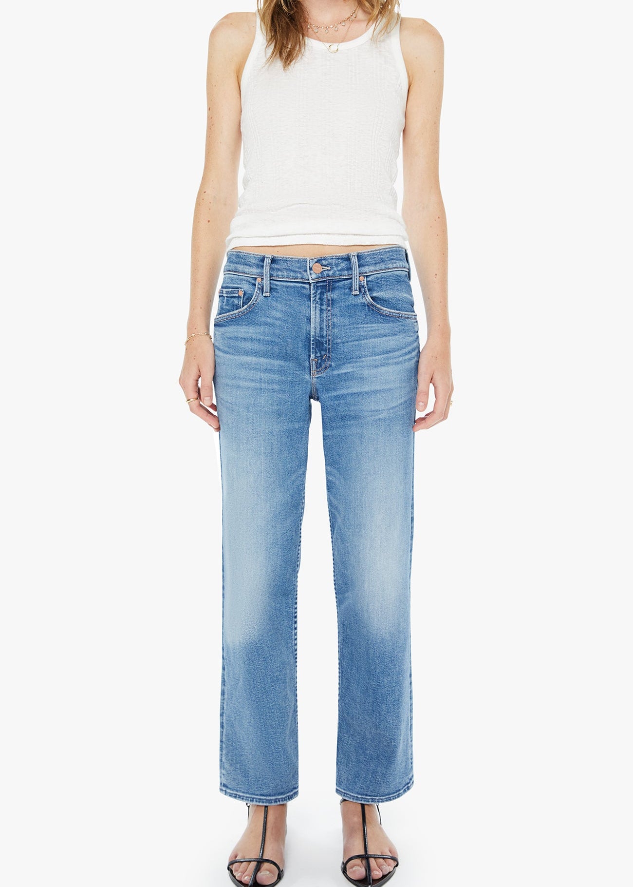 Woman wearing light blue jeans and a white sleeveless top on a white background