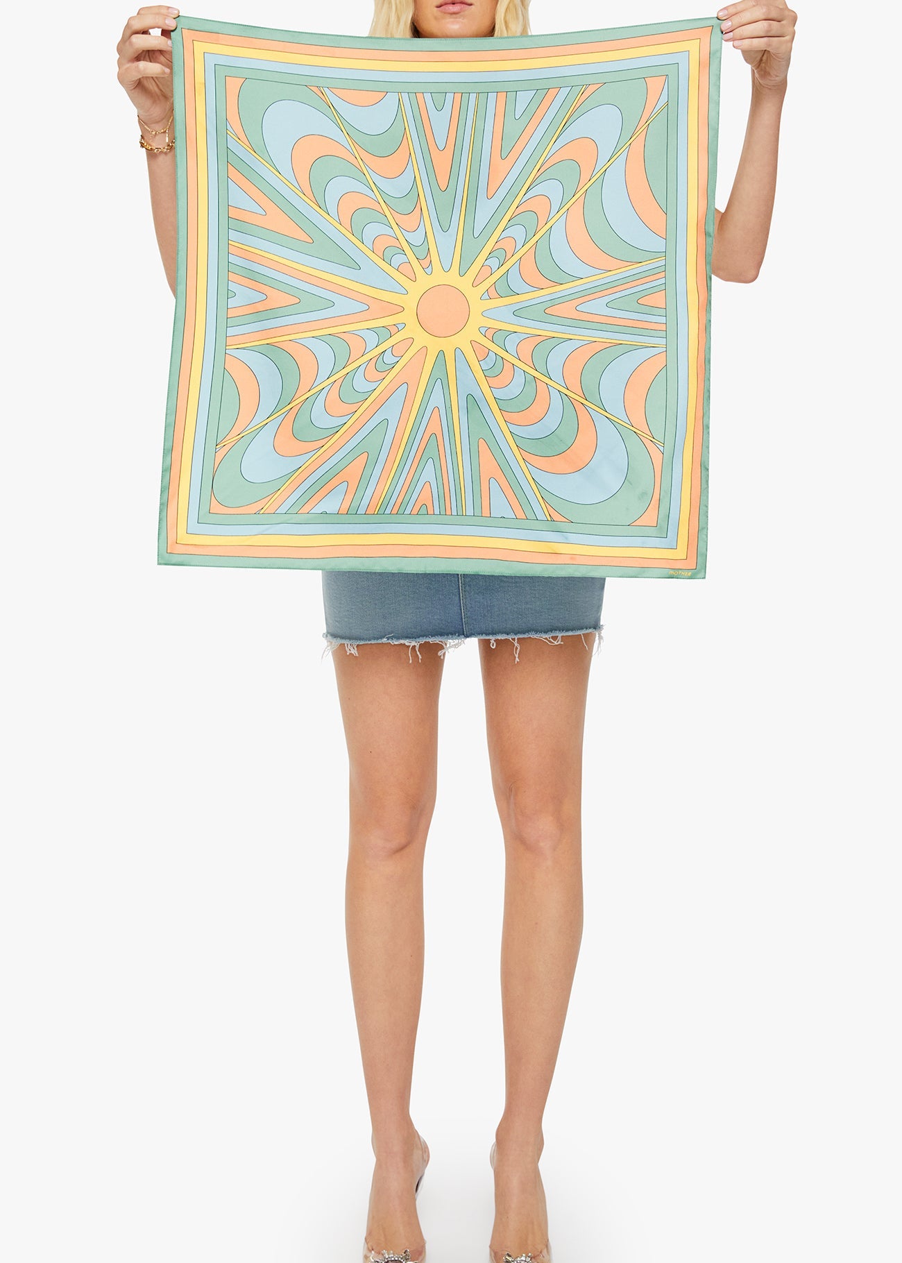 Person holding a colorful square scarf with a geometric pattern on a white background