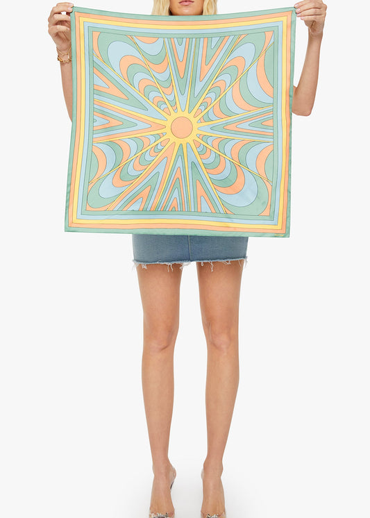 Person holding a colorful square scarf with a geometric pattern on a white background