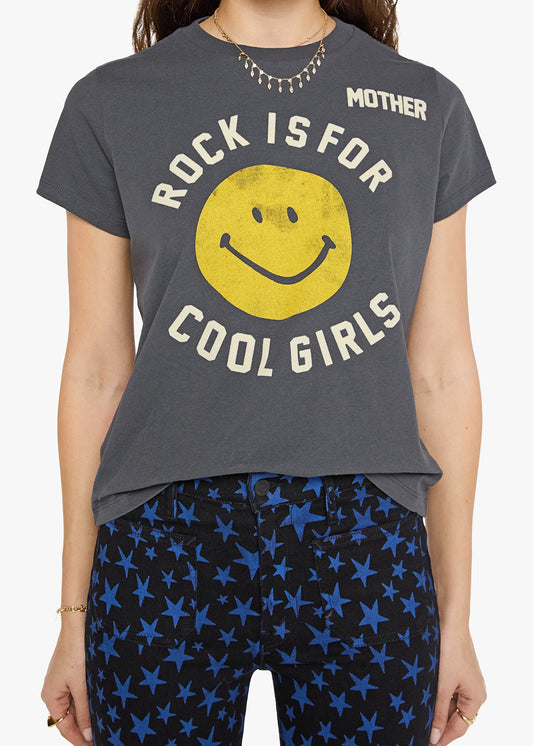 A woman wearing a dark gray graphic t-shirt with a yellow smiley face and the text 'ROCK IS FOR COOL GIRLS' and 'MOTHER', paired with blue star-patterned leggings.
