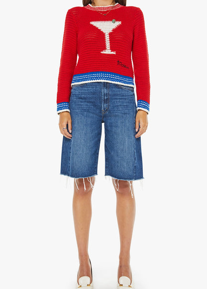 Person wearing a red sweater with a martini glass design and blue shorts on a white background