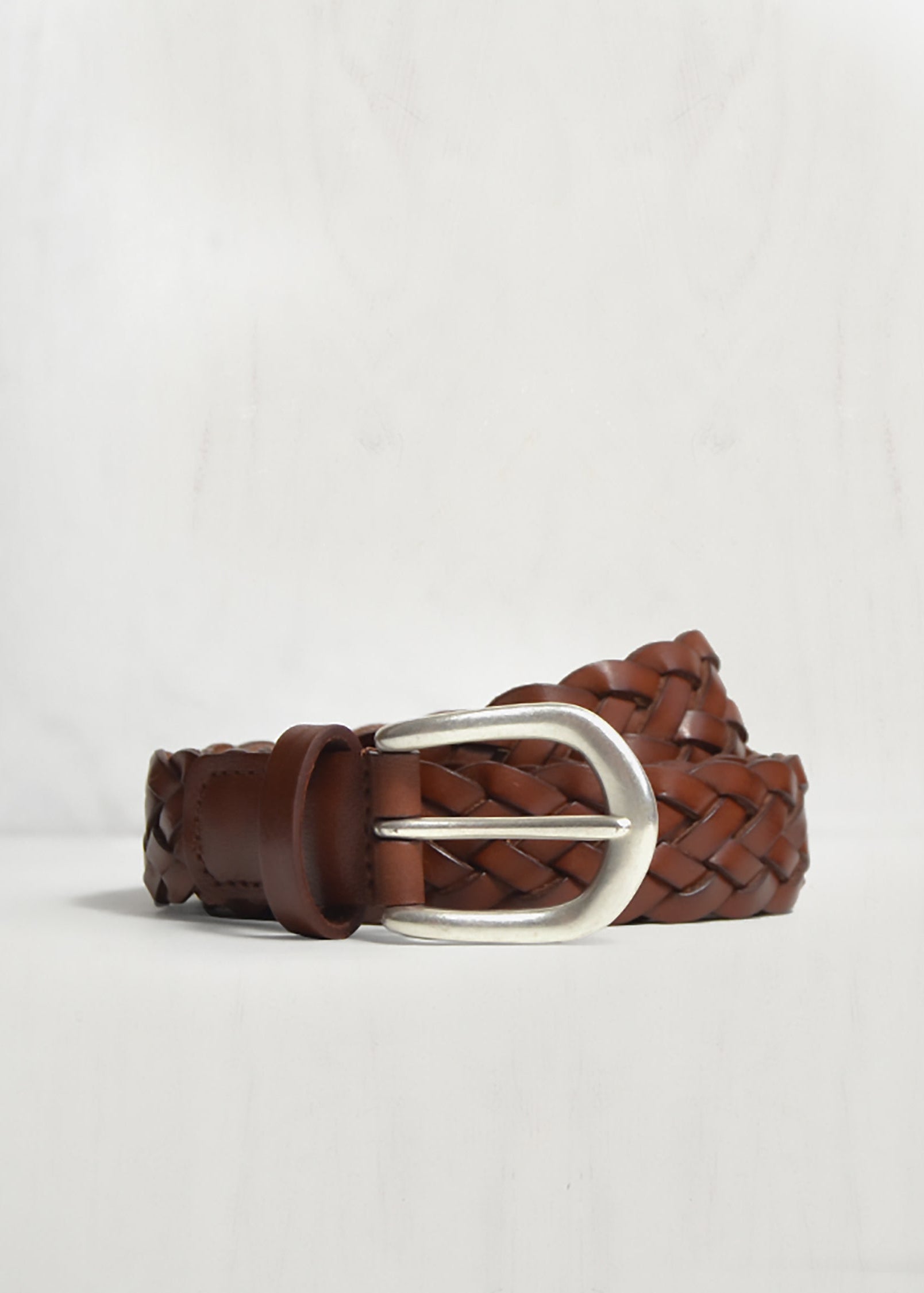 Brown braided belt with a silver buckle on a light gray background