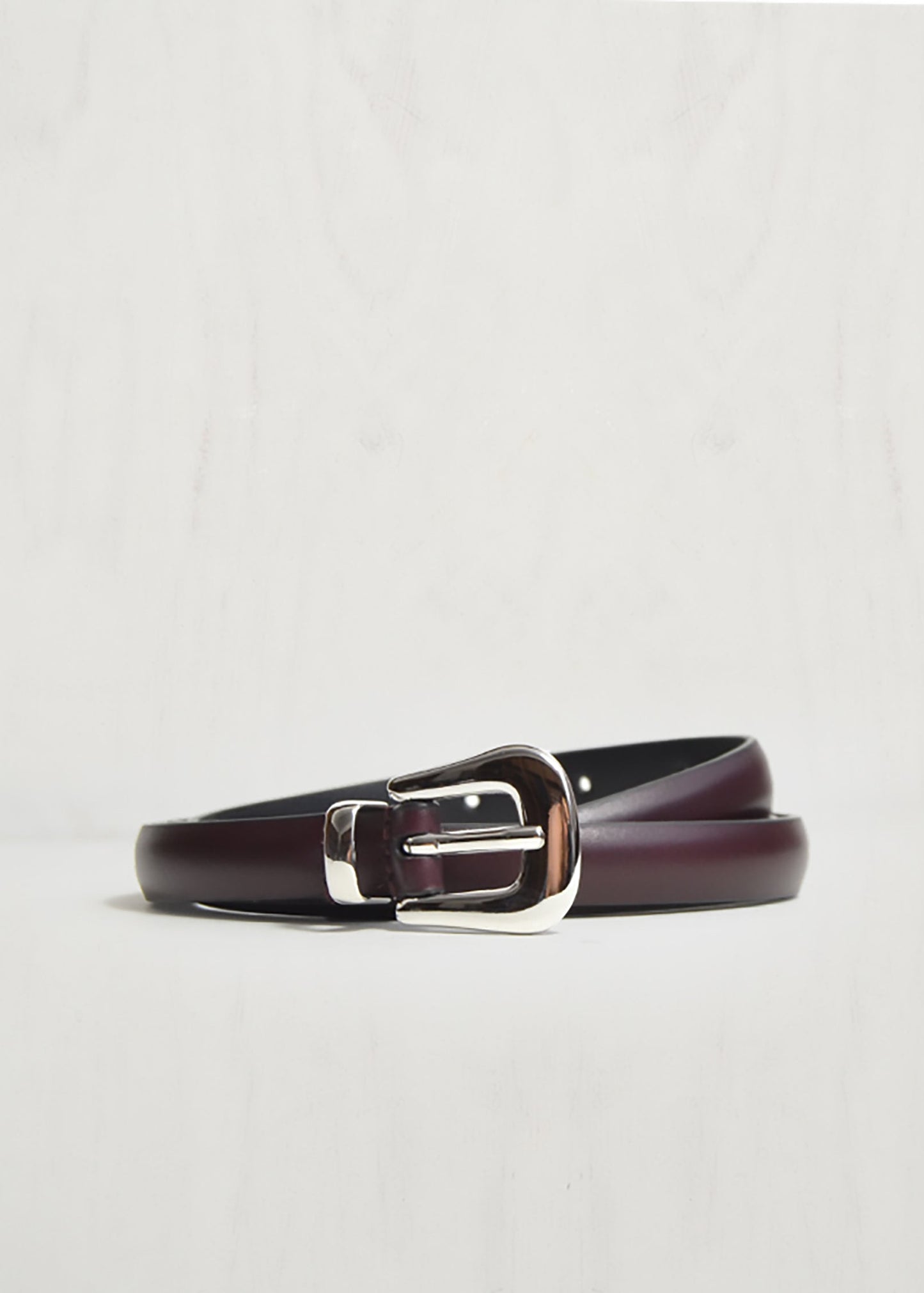 Brown leather belt with silver buckle on a light gray background