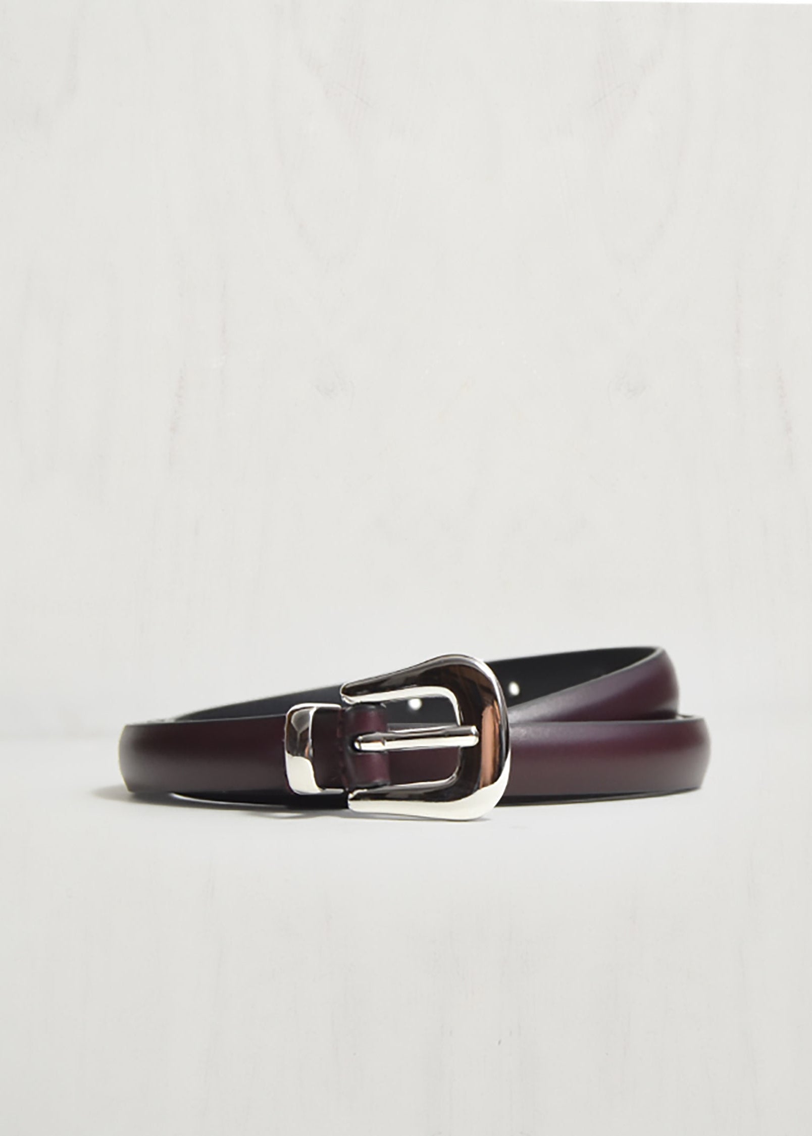 Brown leather belt with silver buckle on a light gray background
