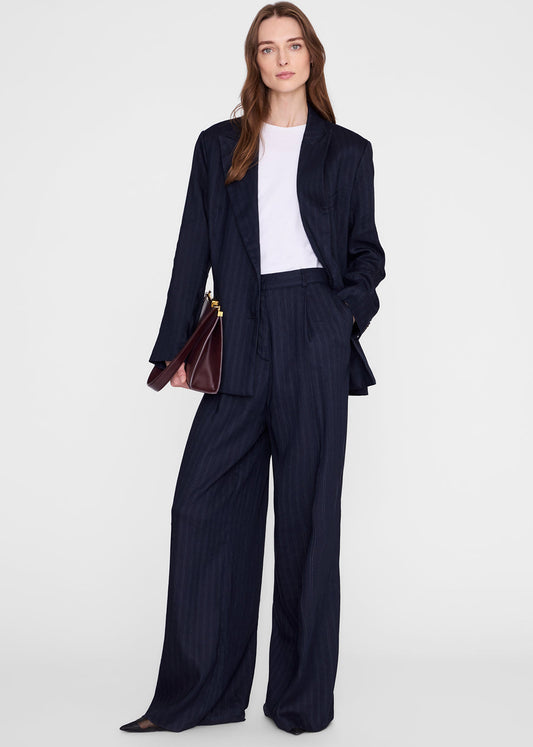 Woman wearing a navy suit with a white top on a light gray background