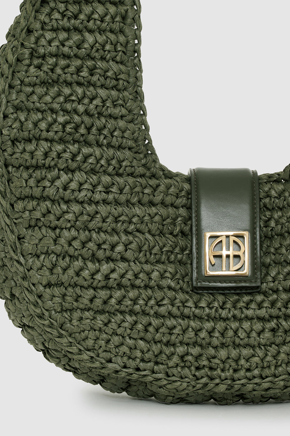 Green woven bag with a gold clasp on a light gray background