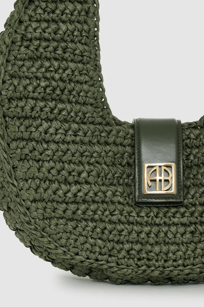 Green woven bag with a gold clasp on a light gray background