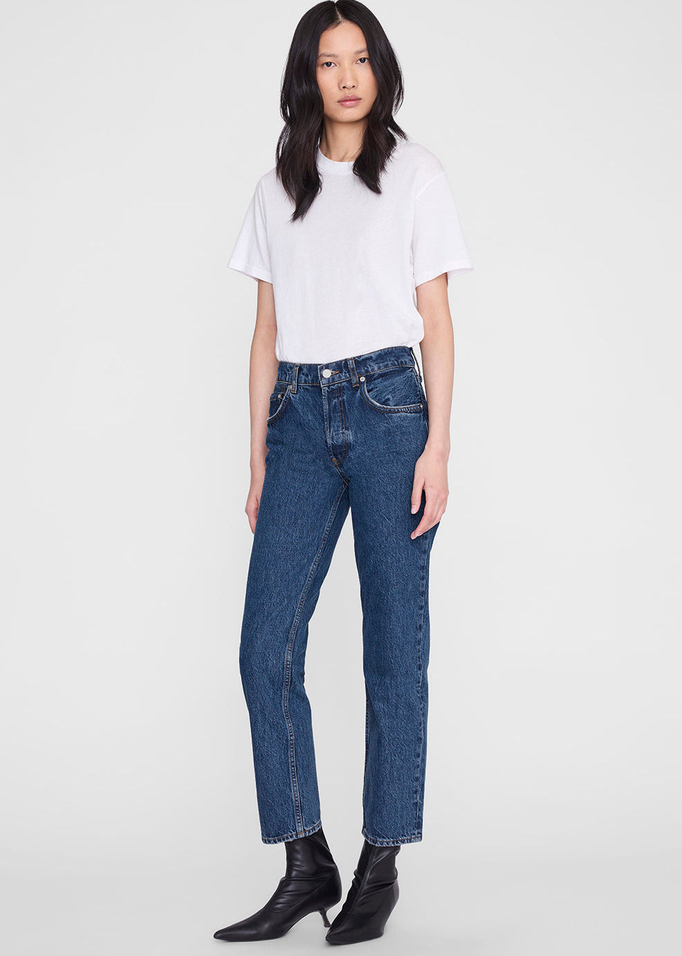 Woman wearing a white t-shirt and blue jeans on a white background