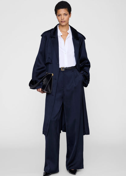 Person wearing a navy coat and pants with a white shirt on a white background
