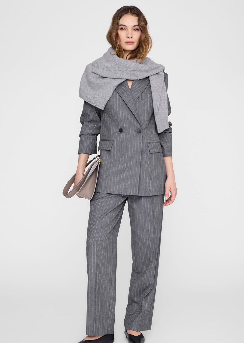 Woman wearing a gray pinstripe suit with a matching scarf on a white background