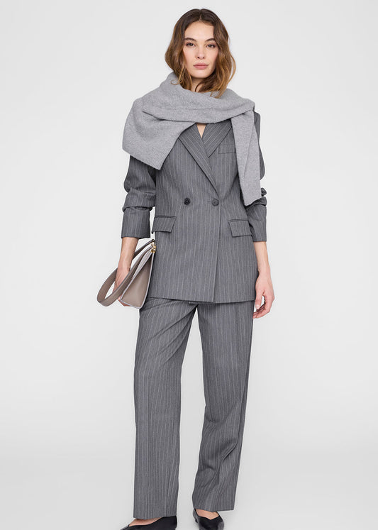 Woman wearing a gray pinstripe suit with a matching scarf on a white background