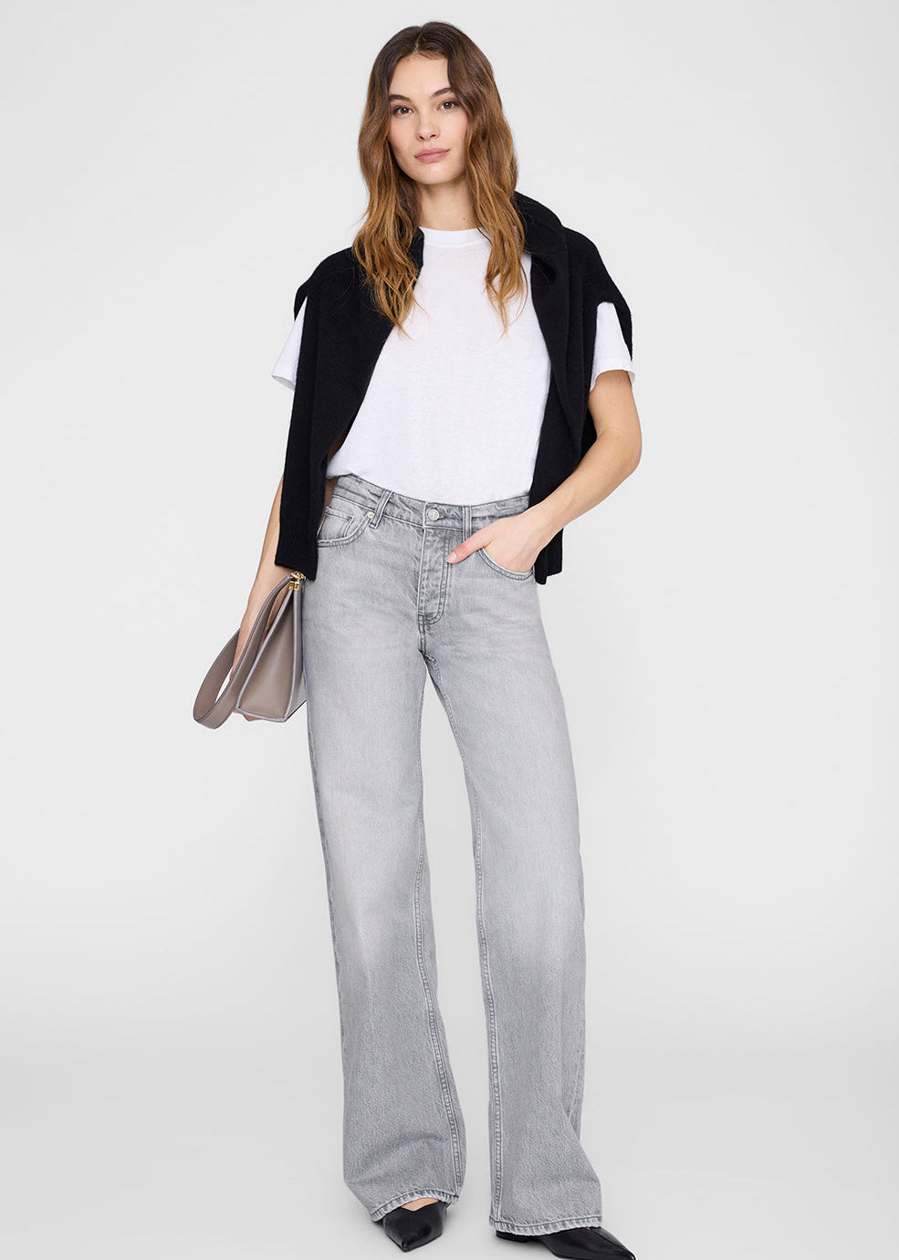 Woman wearing a black cardigan, white t-shirt, and gray jeans on a white background