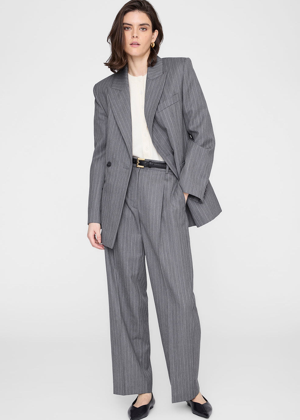 Woman wearing a gray pinstripe suit on a white background