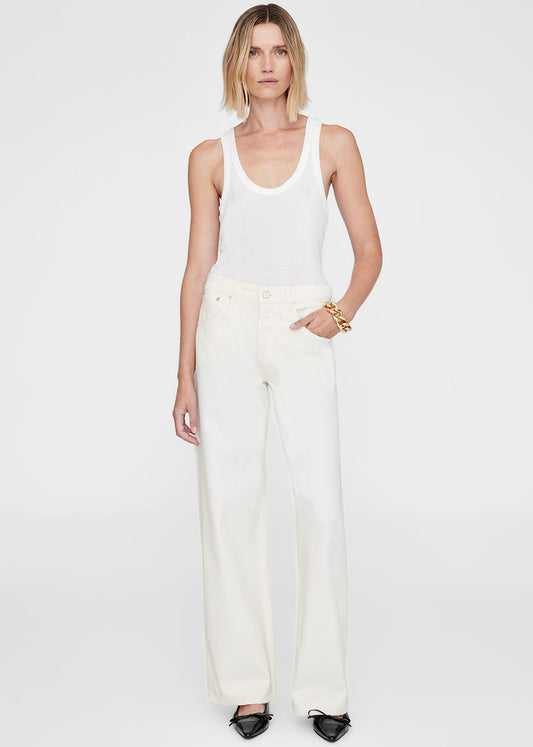 Woman wearing a white tank top and pants on a plain background