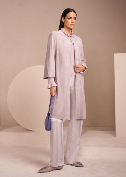 Woman in a light gray outfit holding a blue bag against a neutral background