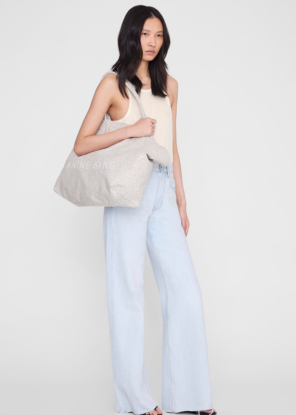 Woman holding a beige tote bag against a white background