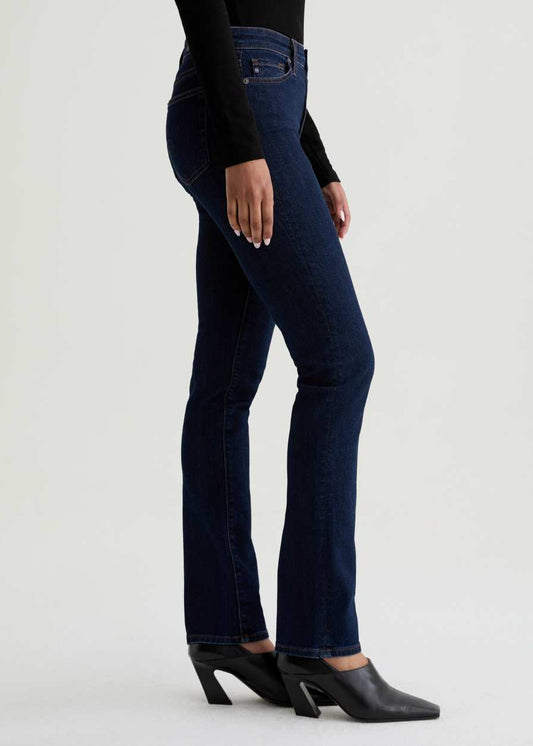 Person wearing dark blue jeans and black shoes on a white background