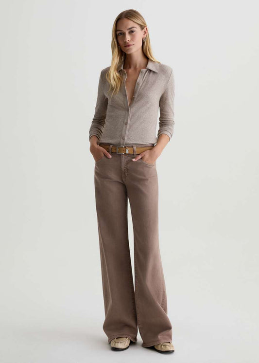 Woman wearing a beige shirt and brown pants on a white background