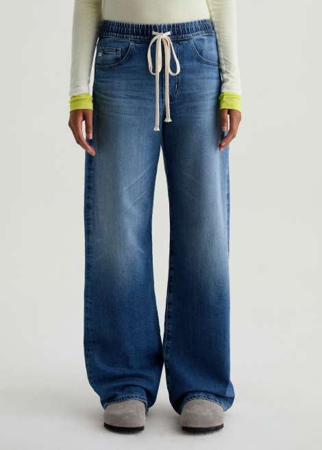 Person wearing blue wide-leg jeans on a plain background