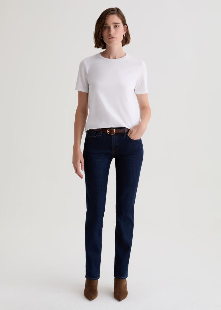 Person wearing a white t-shirt and dark blue jeans on a light gray background