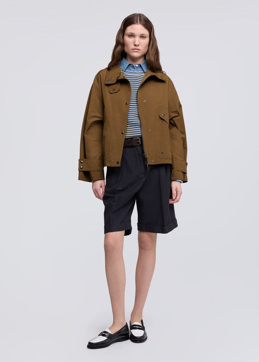 Person wearing a brown jacket and black shorts on a white background