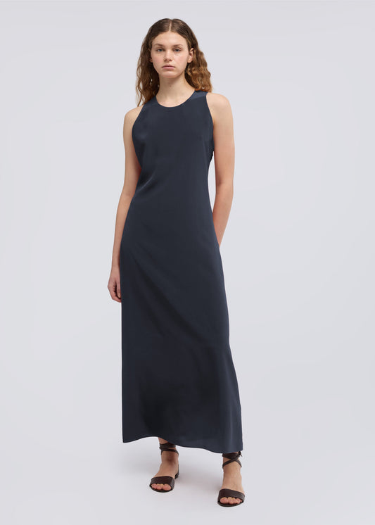 Woman wearing a sleeveless navy dress on a white background