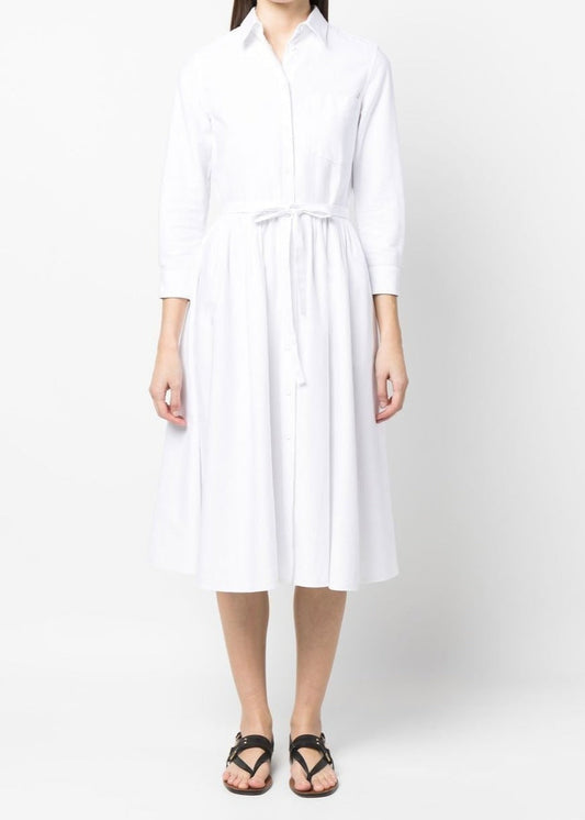 A woman wearing a white, full-skirted, self-tie dress with a crisp, linen fabric.