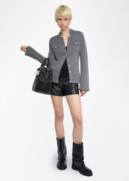Woman wearing a gray jacket, black shorts, and black boots on a white background