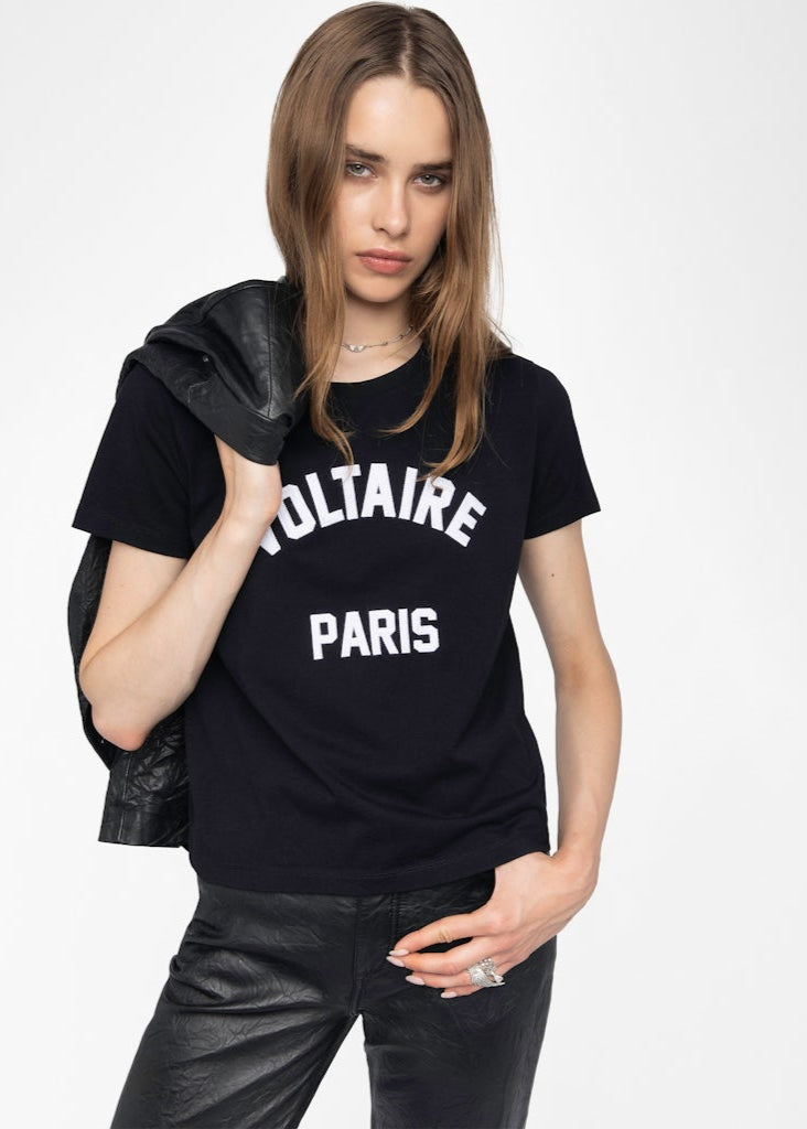 Woman wearing a black t-shirt with 'Voltaire Paris' text on a white background