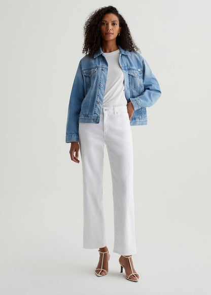Woman wearing a denim jacket, white shirt, and white pants on a white background