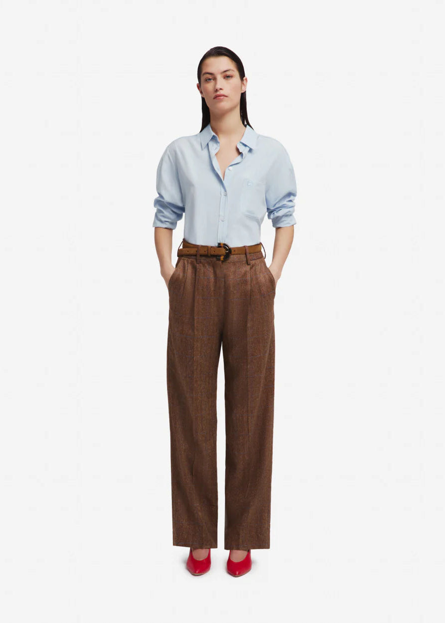 Woman wearing a light blue shirt and brown pants on a white background