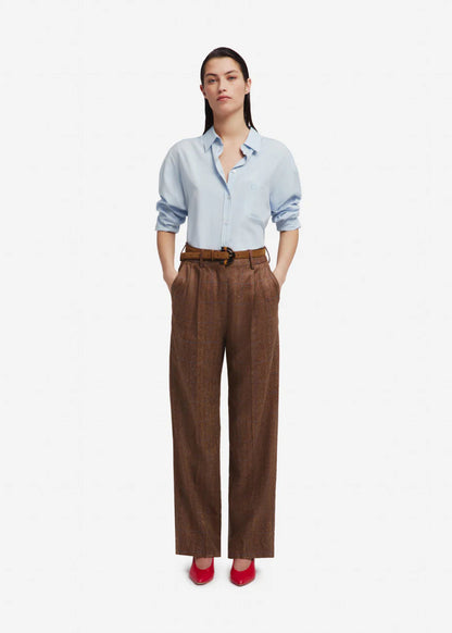 Woman wearing a light blue shirt and brown pants on a white background