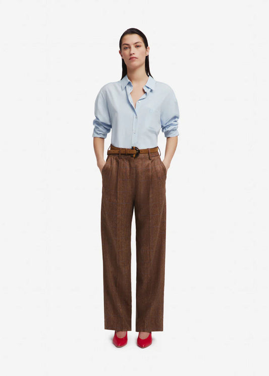 Woman wearing a light blue shirt and brown pants on a white background