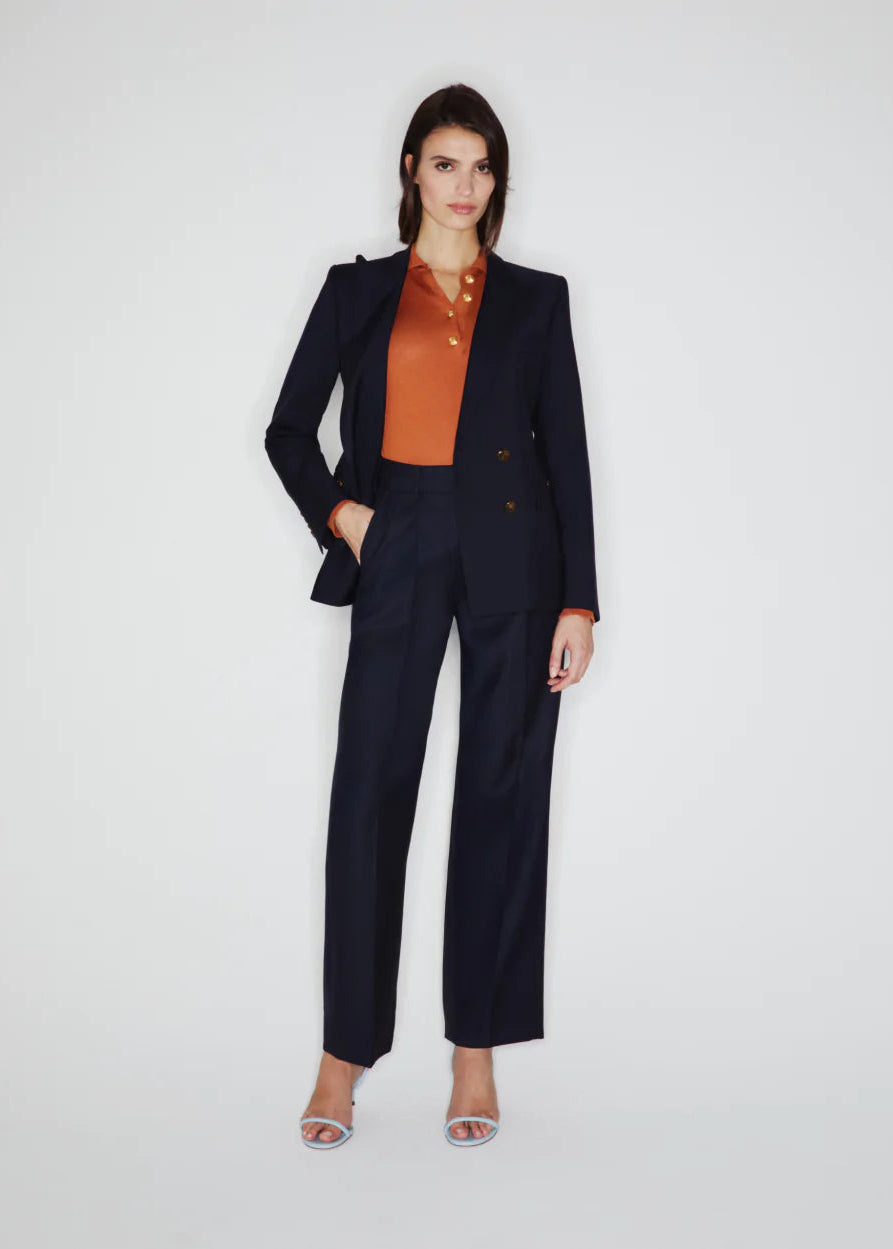 Woman wearing a black suit with an orange blouse on a white background