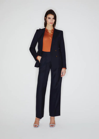 Woman wearing a black suit with an orange blouse on a white background