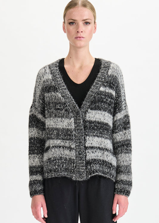 Woman wearing a black and gray striped cardigan over a black top on a white background