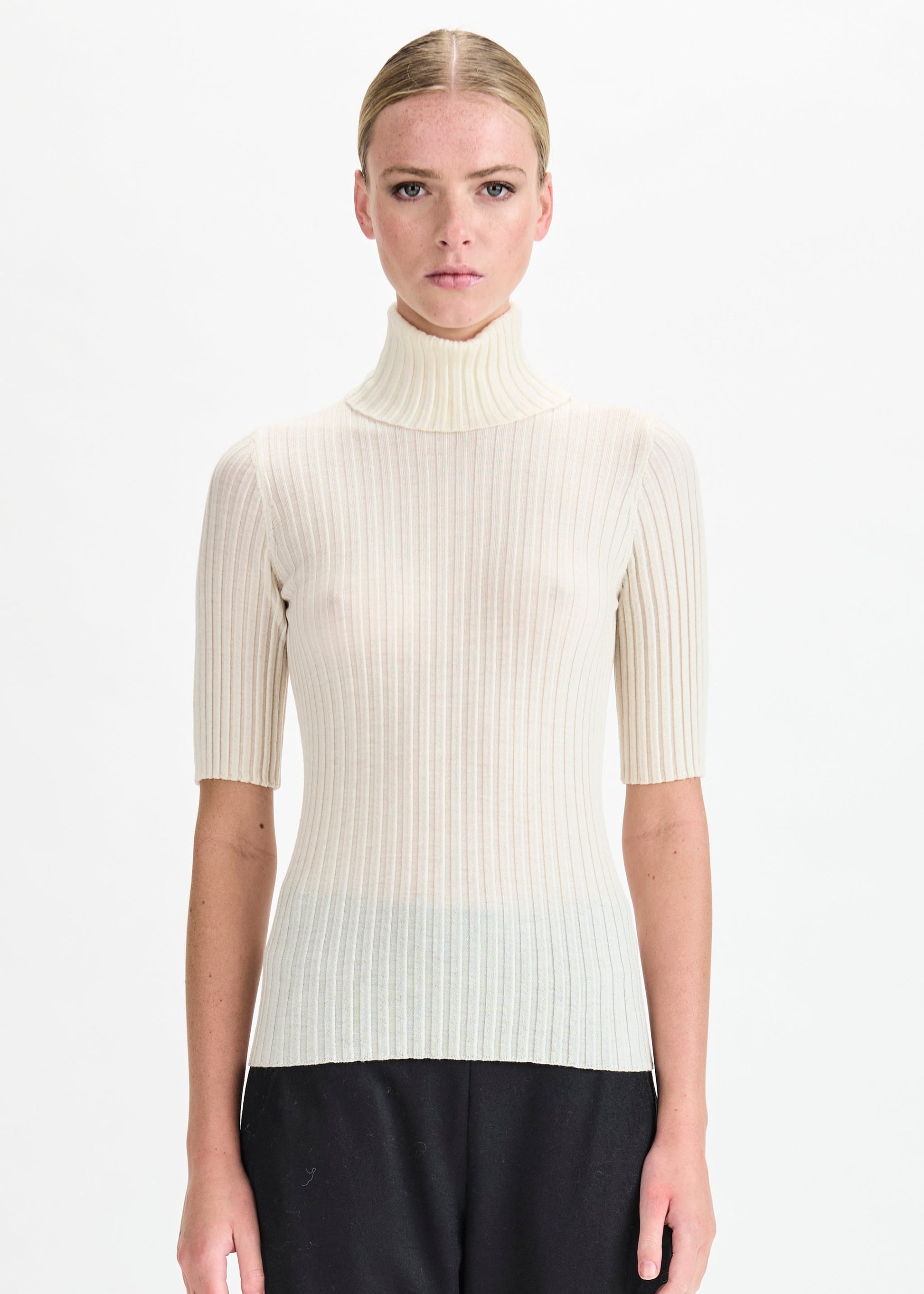 Woman wearing a white ribbed turtleneck sweater on a white background