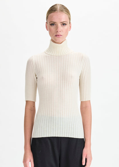 Woman wearing a white ribbed turtleneck sweater on a white background