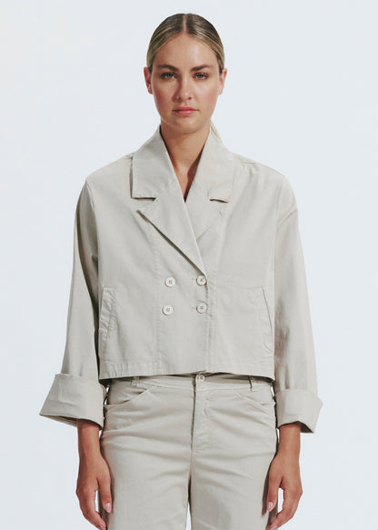 Woman wearing a beige jacket and pants on a white background