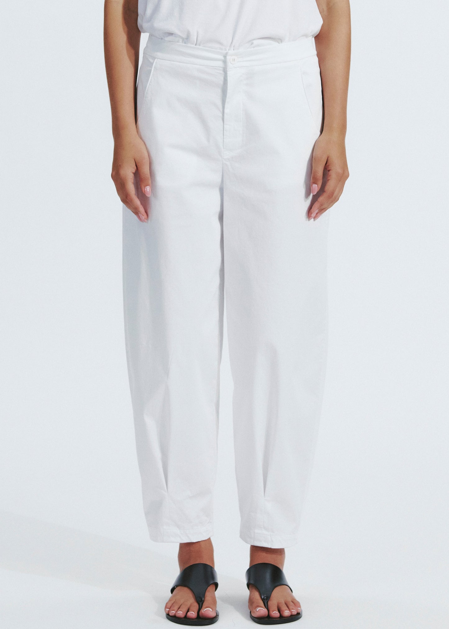 Person wearing white pants on a plain background