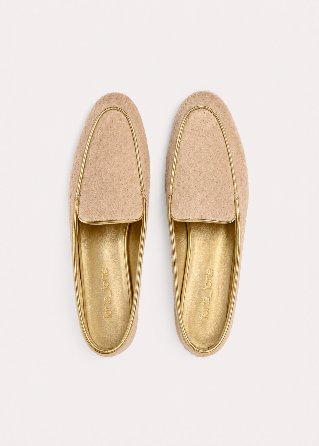 A pair of tan suede slip-on loafers with gold trim and a gold insole, shown from a top-down view on a light off-white background.