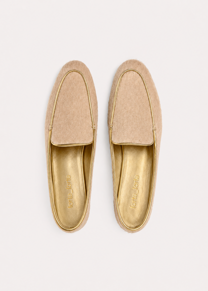 A pair of tan suede slip-on loafers with gold trim and a gold insole, shown from a top-down view on a light off-white background.